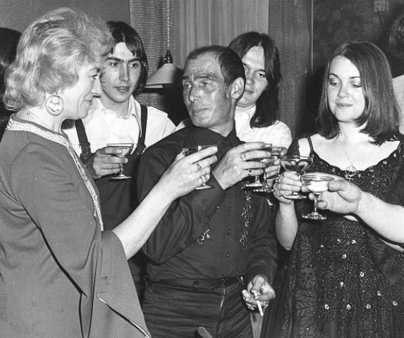 A black-and-white photograph of a gathering from the tradition's history, glasses raised in a toast.